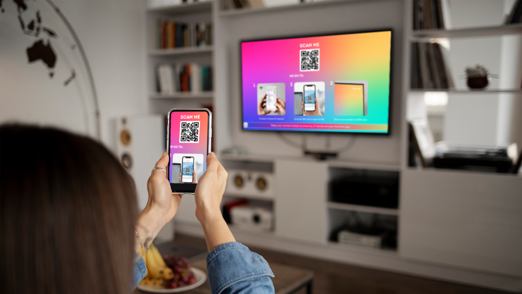 女性がスマートフォンでQRコードをスキャンしてホテルのテレビにキャスト、キャスティング対応ホスピタリティTVシステム