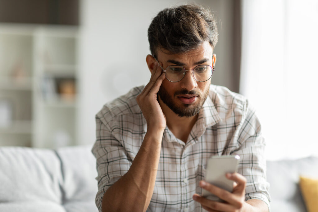 Mann frustriert, während er auf sein Telefon schaut.
