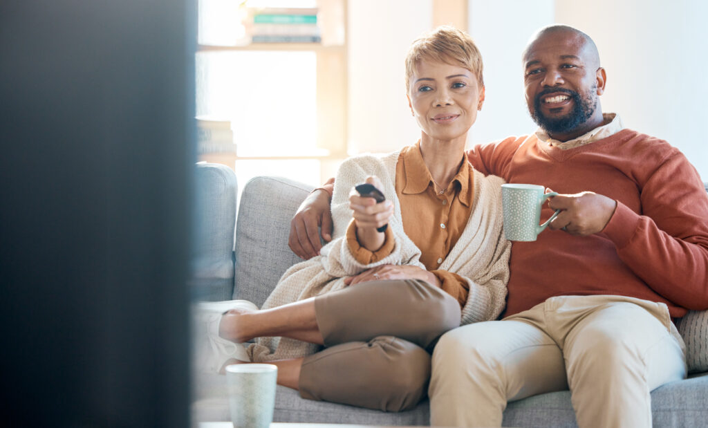 キャスティングシステムのあるホテルで楽しそうにテレビを見るカップル